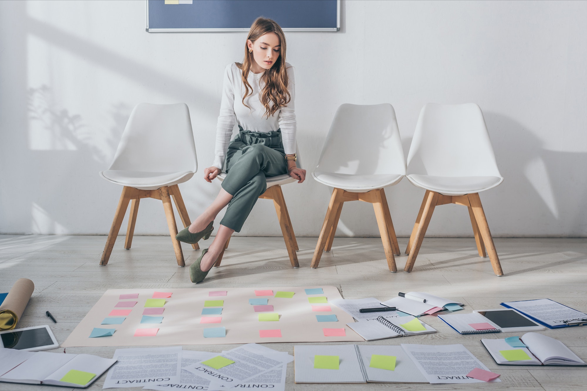 attractive-scrum-master-sitting-on-chair-near-sticky-notes-on-floor.jpg